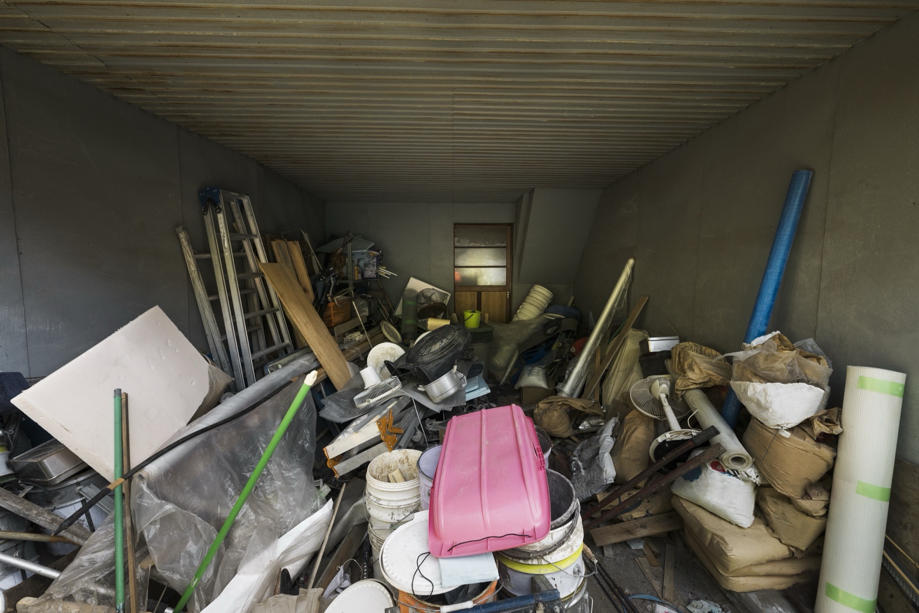 A garage packed with household clutter, furniture and building offcuts ready for removal